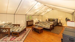 A tented accommodation with a bed, two sofas, a table, and a dresser. - Mountain Tent Retreat: Game Room Near Ocoee River (Copperhill)