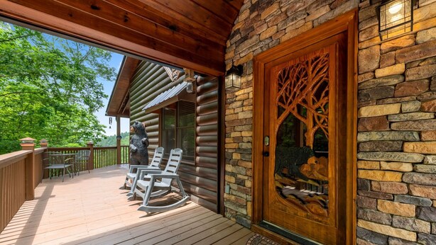 Um deck de madeira com cadeiras de balanço e uma parede de pedra com uma porta decorativa.