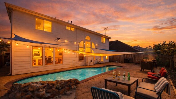 Ein Haus mit Swimmingpool, Sitzgelegenheiten im Freien und Lichterketten.