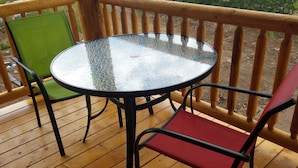 A round glass table with metal legs, surrounded by wooden chairs with green and red cushions. - "Treehouse" Cozy Retreat for 2 Near Yellowstone! (Island Park)