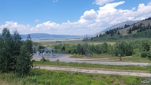 A rural landscape with a road, power lines, and a small vehicle. - "Treehouse" Cozy Retreat for 2 Near Yellowstone! (Island Park)
