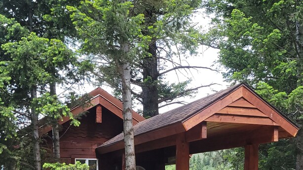 A wooden cabin with a covered porch and a gravel driveway. - "Treehouse" Cozy Retreat for 2 Near Yellowstone! (Island Park)