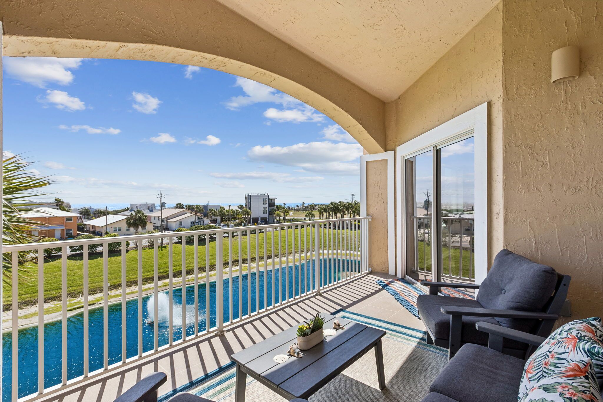 Un balcón con vista a una piscina, una mesa de comedor y una silla.
