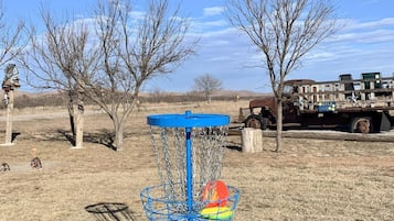 Enjoy a round of disc golf at our resort, featuring a challenging basket in a scenic grassy field.