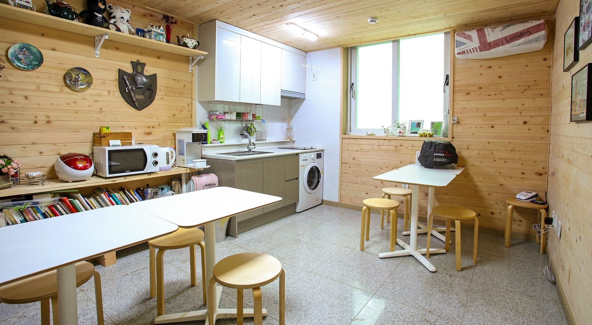 A compact kitchen with a washing machine, microwave, and a dining area with stools.