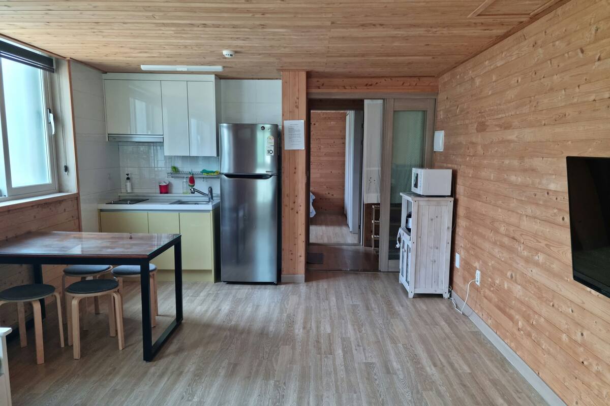 Een moderne keuken met houten wanden, een roestvrijstalen koelkast en een eethoek met krukken.