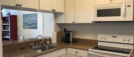 A kitchen with white cabinetry, a microwave, an oven, a dishwasher, and a sink.