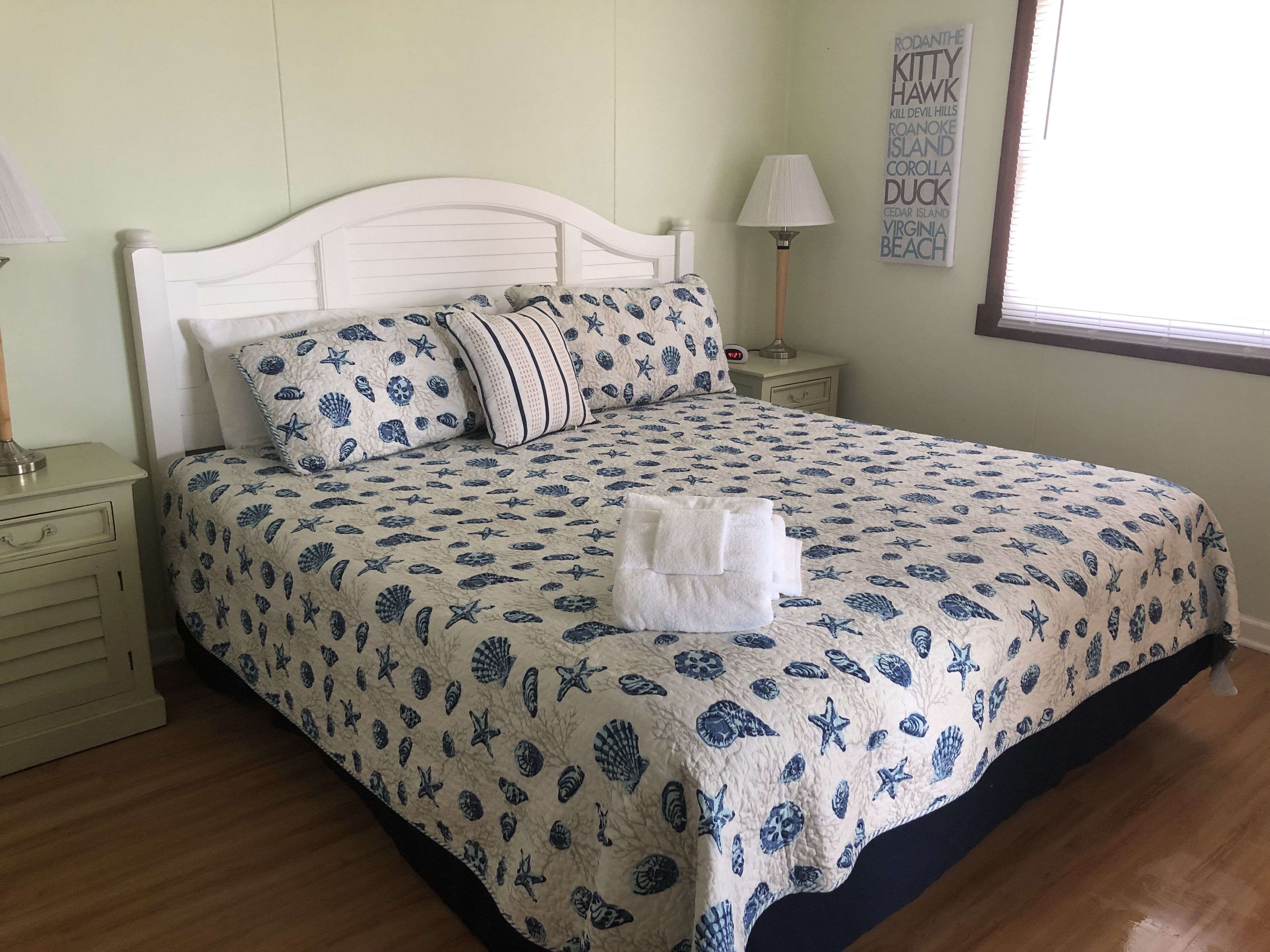 Un lit bien fait, recouvert d’une courtepointe aux motifs nautiques bleus et blancs, avec un oreiller blanc et une serviette blanche pliée posée sur le lit.