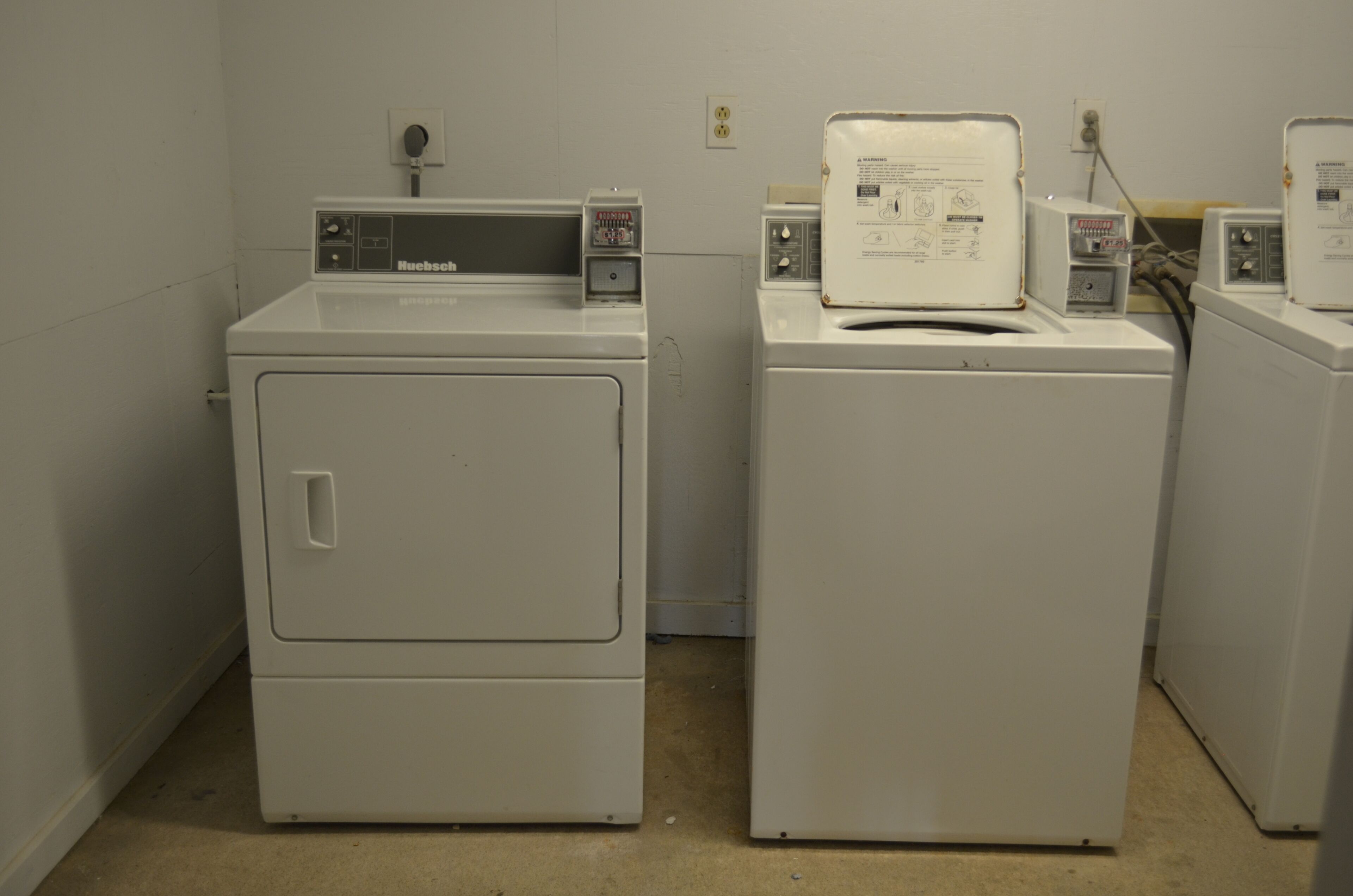 A laundry room with two front-loading washing machines and a dryer.