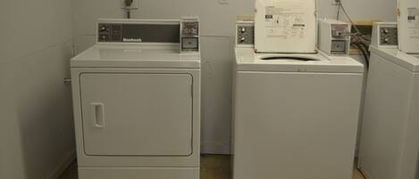 A laundry room with two front-loading washing machines and a dryer.