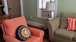 A living room with a peach-colored armchair, a matching ottoman, a beige sofa, and a patterned throw pillow. - Cripple Cove Apartment in historic home across from harbour in Gloucester, MA (Gloucester)