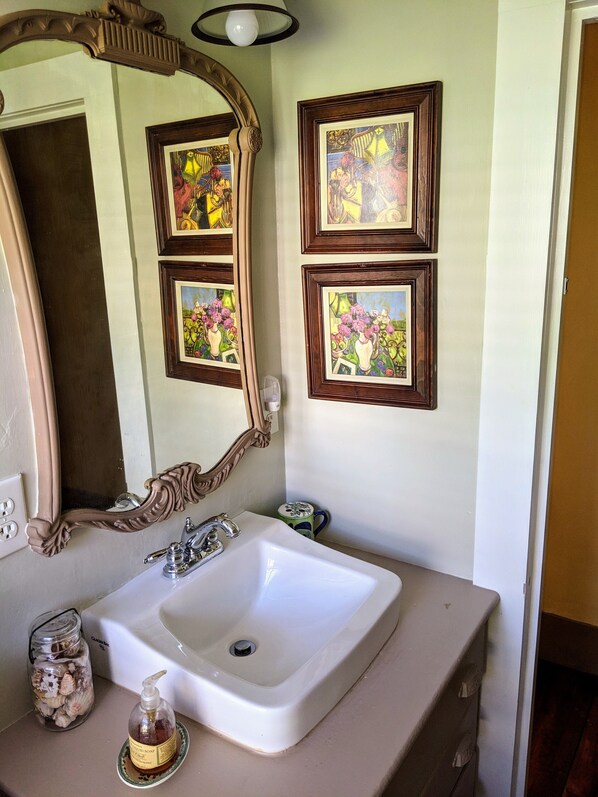 A bathroom with a white sink, a decorative mirror, and three framed pictures on the wall. - Cripple Cove Apartment in historic home across from harbour in Gloucester, MA (Gloucester)