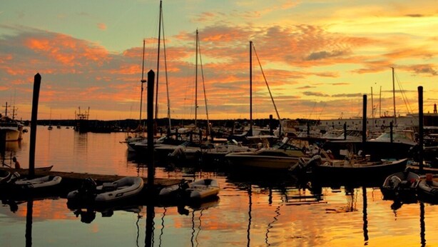 A marina with boats docked at the pier, reflecting the sunset sky. - Cripple Cove Apartment in historic home across from harbour in Gloucester, MA (Gloucester)