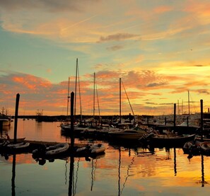 A marina with boats docked at the pier, reflecting the sunset sky. - Cripple Cove Apartment in historic home across from harbour in Gloucester, MA (Gloucester)