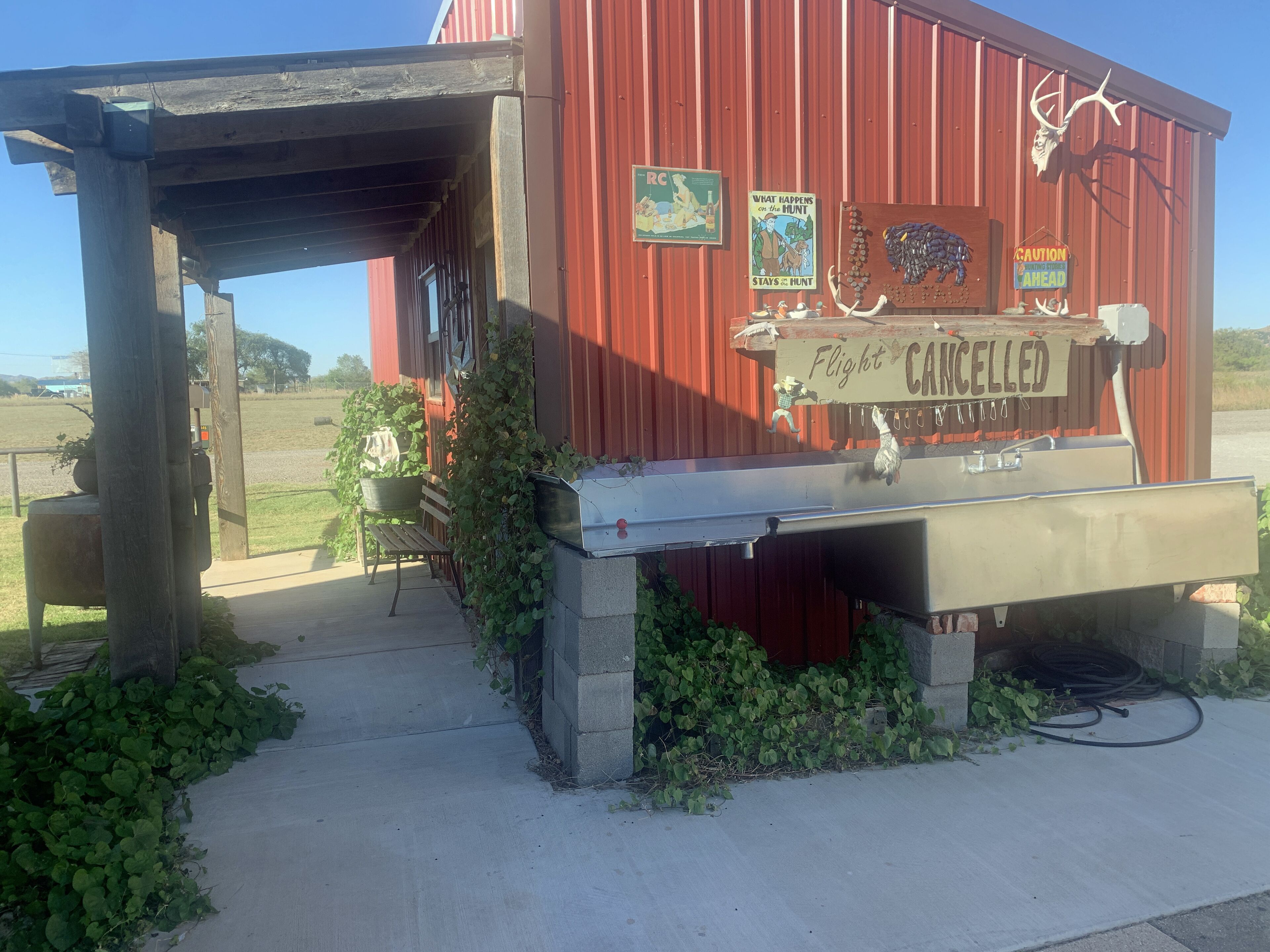 A red building with a 'Flight Cancelled' sign, a wooden bench, and a metal grill.
