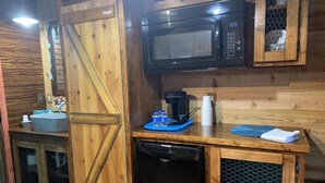 A compact kitchen with a microwave, coffee maker, and dishwasher. - Chief Cabin at The Lazy Buffalo Explore the Wichita Mountains Relax & Unwind (Cache)