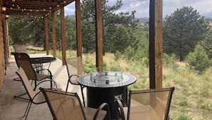 An outdoor patio with a round table and chairs, surrounded by wooden beams and string lights. - Enjoy a private mountain retreat at Paul's Cabin! (Hartsel)