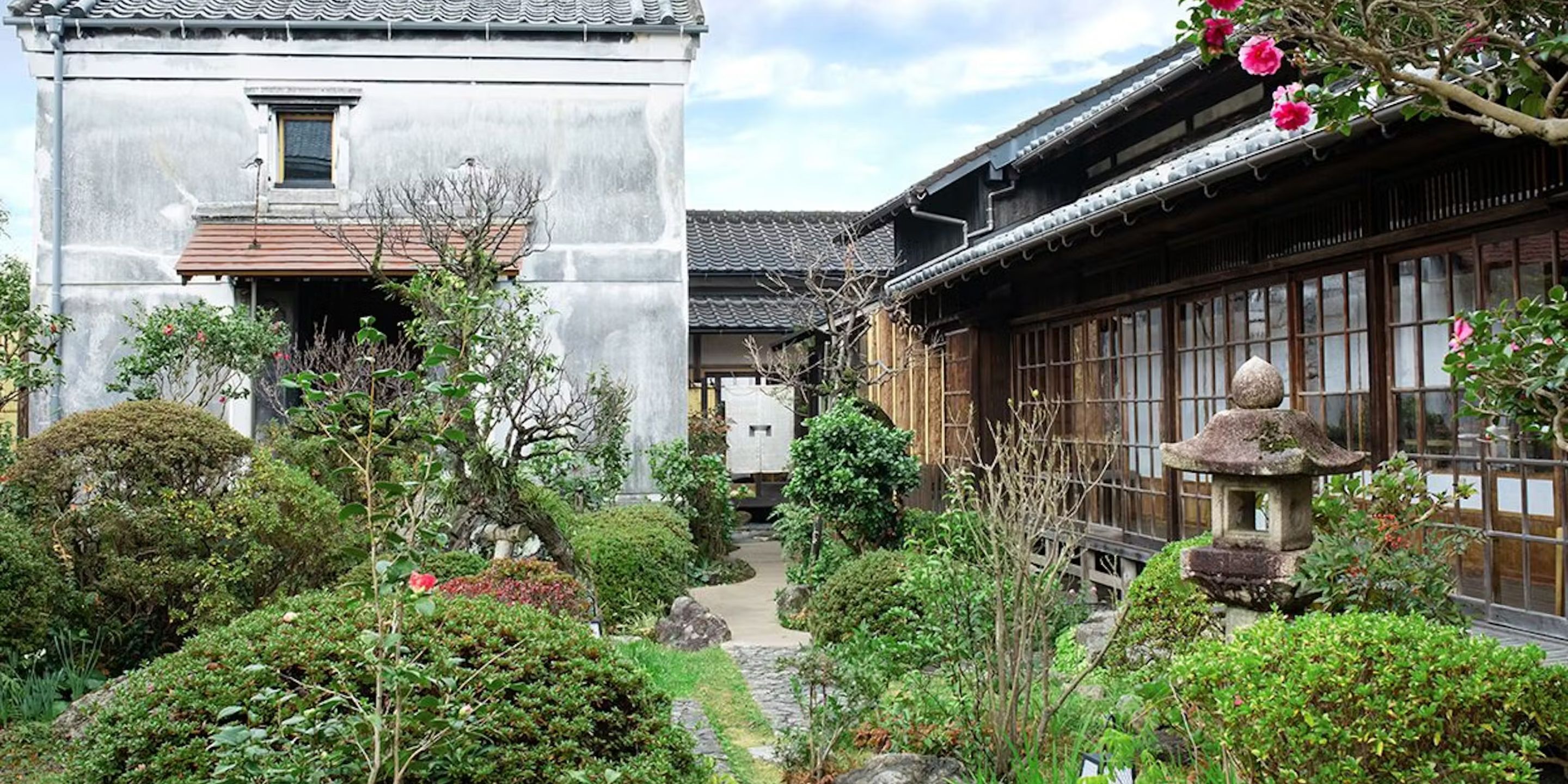 A traditional Japanese building with a garden pathway leading to a wooden structure with sliding doors.
