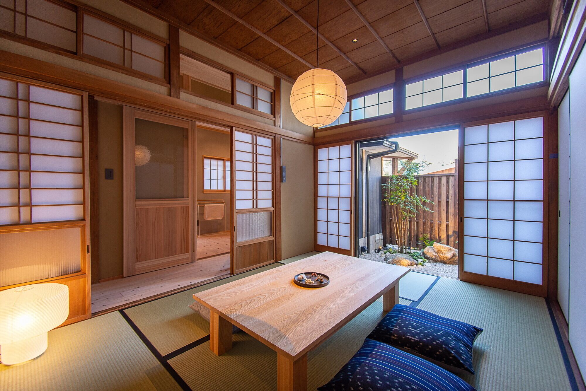Une pièce de style japonais traditionnel, avec un sol recouvert de tatamis, une table en bois et des paravents en papier.
