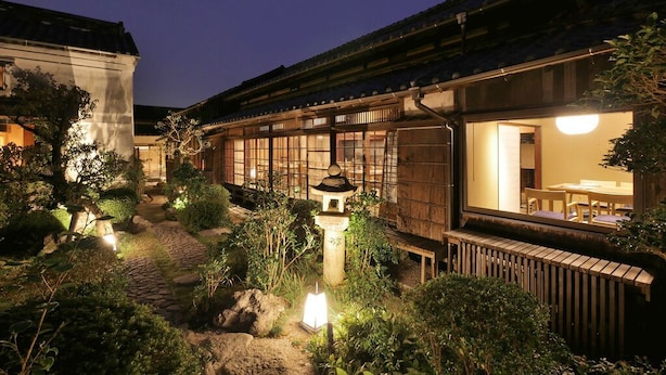 A traditional Japanese ryokan with tatami mat rooms, a wooden exterior, and a garden with a lantern path.