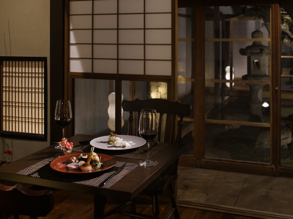 Une salle à manger traditionnelle japonaise, avec des tatamis, une table basse et une porte coulissante donnant sur un jardin.