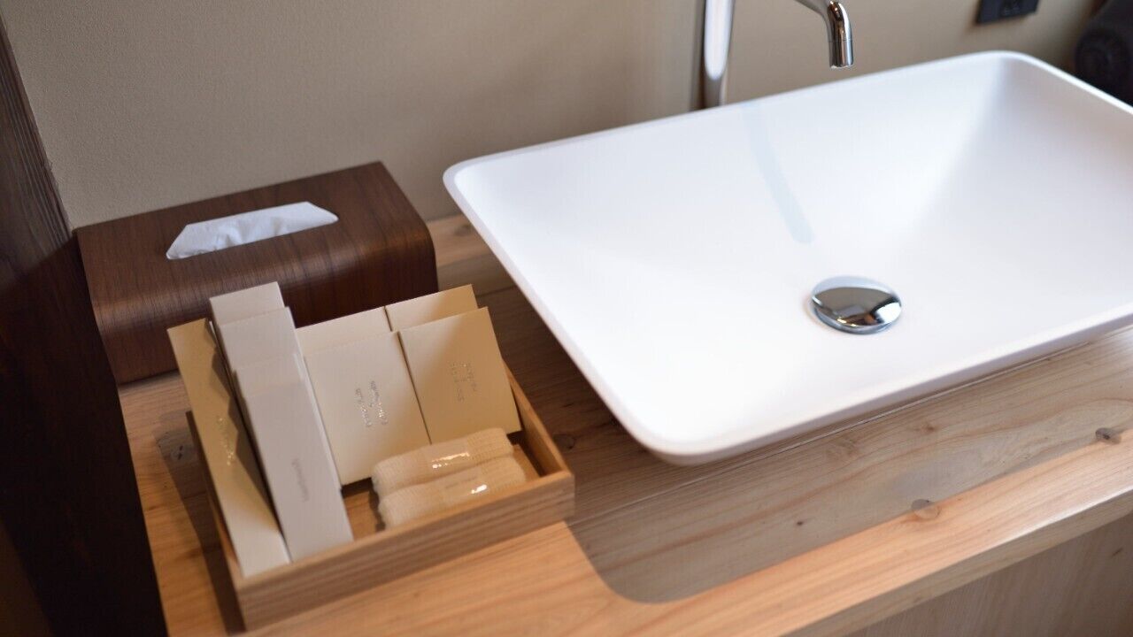 A bathroom with a white sink, a wooden tray with toiletries, and a tissue box.