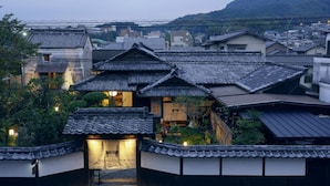 A traditional Japanese building with a tiled roof, a central entrance, and a sign indicating it is a hotel.