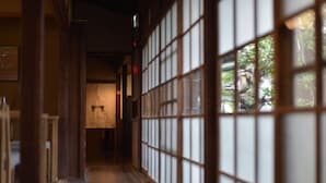 A traditional Japanese interior with sliding doors, wooden flooring, and a view through the doors.