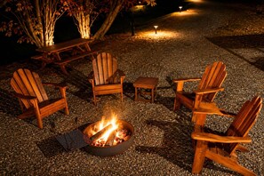 Un espace extérieur aménagé avec du gravier, comprenant des chaises Adirondack en bois et un foyer.