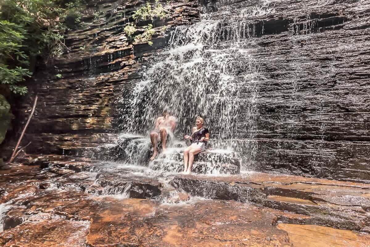 A waterfall with a person sitting on rocks.