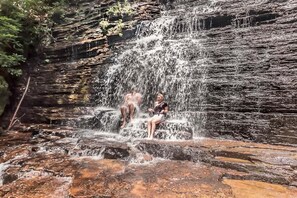 Una cascada con una persona sentada sobre rocas.