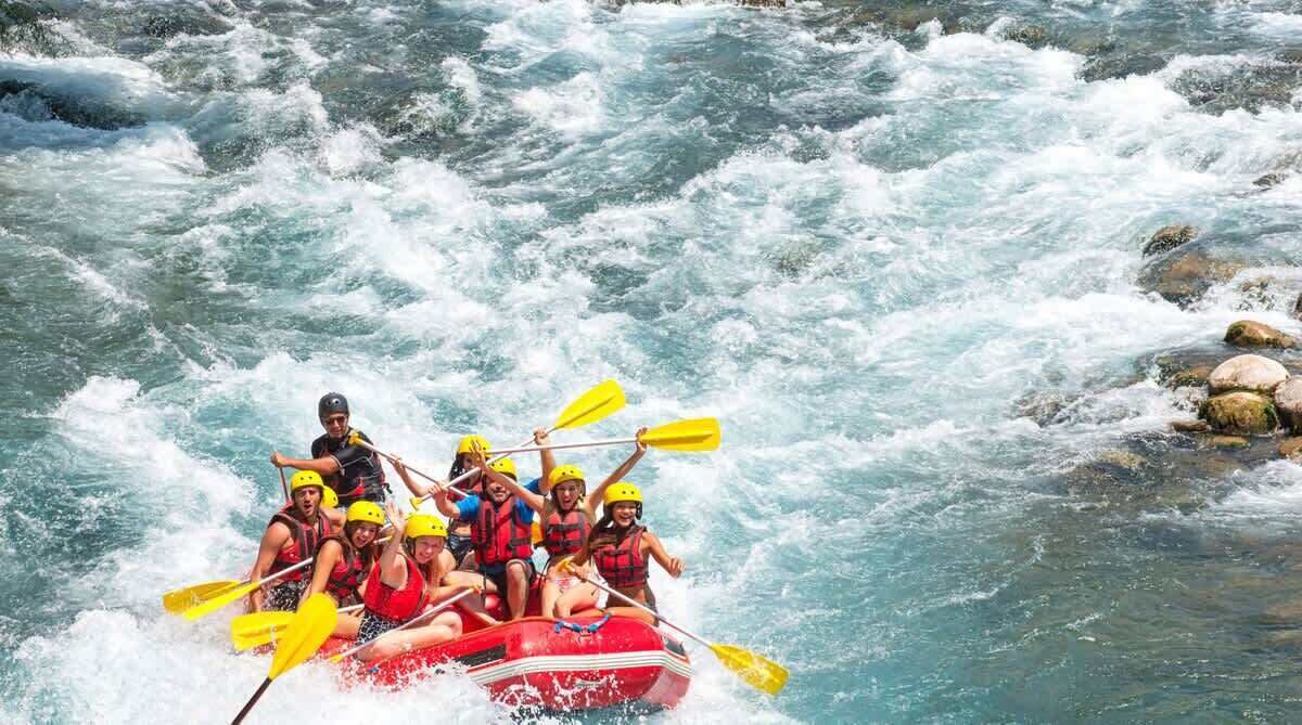 A group of people in a red raft navigating a river with rapids.
