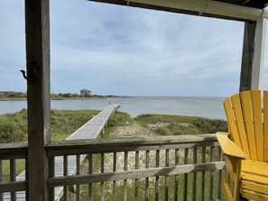 A wooden deck with a view of a body of water and a distant house. - Seahorse is an end unit with breathtaking views of the Pamlico Sound! (HATTERAS)
