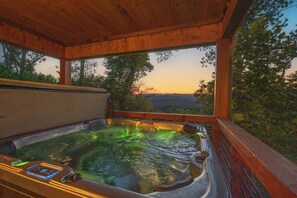 A hot tub with a digital control panel, surrounded by a wooden deck with a view of trees and a sunset in the background. - New Heights - Blue Ridge GA (Blue Ridge)