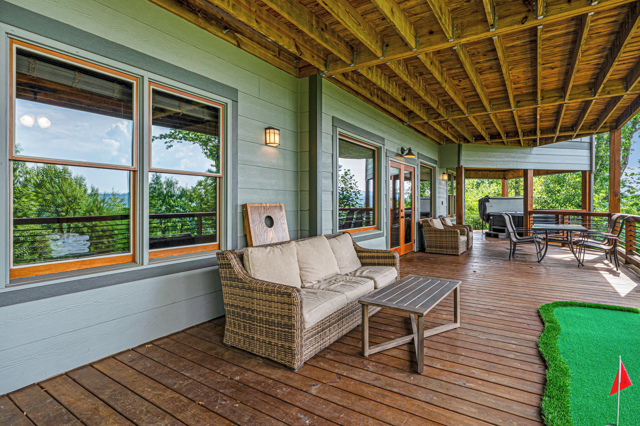 A covered deck with a wicker sofa, a table, and outdoor seating.