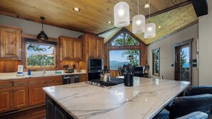 A spacious kitchen with wooden cabinets, a marble island, and pendant lighting. - New Heights - Blue Ridge GA (Blue Ridge)