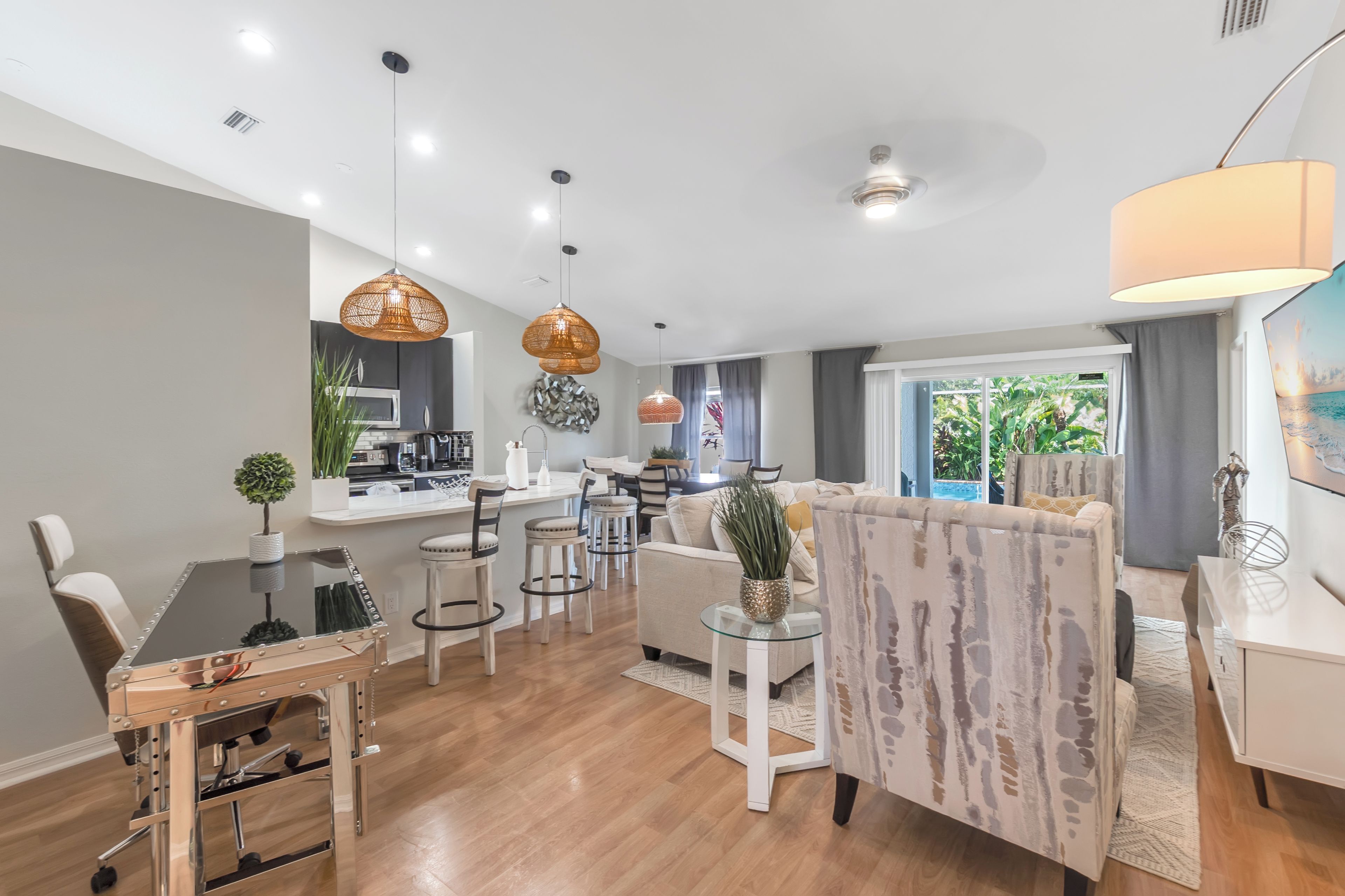 A modern living room with a dining area, kitchen, and a large window with a view.