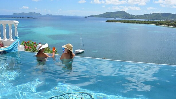 Una piscina infinita con vistas al mar tranquilo y a islas distantes.