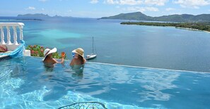 Una piscina infinita con vistas al mar tranquilo y a islas distantes.