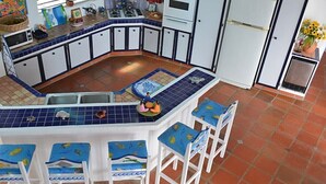 Una cocina con una isla azul con azulejos, armarios blancos y suelo de baldosas.