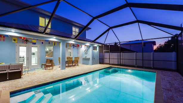 A swimming pool with a covered patio area, a dining table, and chairs. - SEASONAL RENTAL - Spacious Private Pool Home - WALK TO BEACH & MERCATO (Naples)