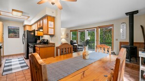 A spacious kitchen with wooden cabinets, a black refrigerator, and a stove. There is a dining table with chairs, a vase, and a "WELCOME" sign. - Pickle Ball Courts, Peaceful Deck Next to Creek! (Durango)