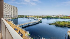 A waterfront view from a balcony with a wooden deck, a pier, and a large hotel building in the background. -   Family Friendly 2Bedroom +Bunks, High Chair,Crib,Beach Chairs,Towels and Games (Panama City Beach)