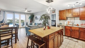 A spacious kitchen with wooden cabinets, a central island, and a dining area with a table and chairs. -   Family Friendly 2Bedroom +Bunks, High Chair,Crib,Beach Chairs,Towels and Games (Panama City Beach)