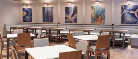 A modern restaurant with booths and tables, wooden flooring, and abstract wall art.