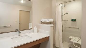A modern bathroom with a sink, mirror, shower, and a towel rack.
