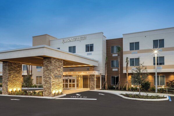 Un hôtel Fairfield Inn & Suites de la chaîne Marriott, doté d’un design moderne, de piliers en pierre et d’une entrée bien éclairée.
