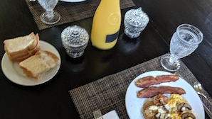 A round dining table with a black tablecloth, two plates of breakfast food, a yellow bottle, and two clear glasses. - The Prospect Room -  HSI (Idaho Falls)