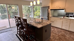 A modern kitchen with a large island, bar stools, and a view of the outdoors.