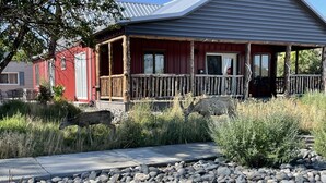 Une cabane rustique dotée d’un porche en bois et d’un sentier de pierres menant à l’entrée.